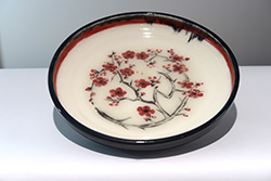 Plum blossom design in carmine and black under a clear glaze, with a black glossy glaze on outside and rim.